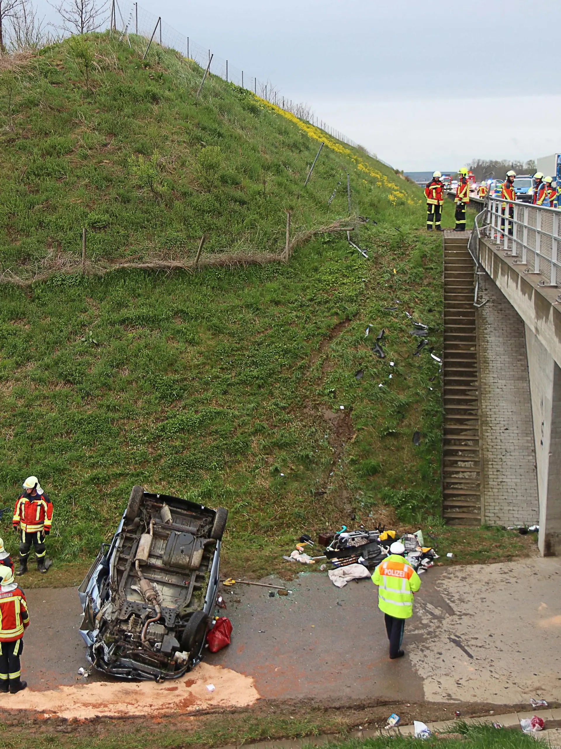 Feuerwehrleute und Polizei stehen an einer Unfallstelle an der Autobahn 8. Zwischen der Anschlussstelle Burgau und der Anschlussstelle Günzburg war eine 64-Jährige in ihrem Fahrzeug von der Fahrbahn abkommen. Sie fuhr ca. 200 Meter parallel zur Fahrbahn weiter, ehe das Auto an einer Brücke rund fünf Meter einen Abhang hinabstürzte. Auf einer Straße unter der Autobahn blieb das Fahrzeug auf dem Dach liegen. Alle vier Insassen wurden bei dem Unfall schwer verletzt.