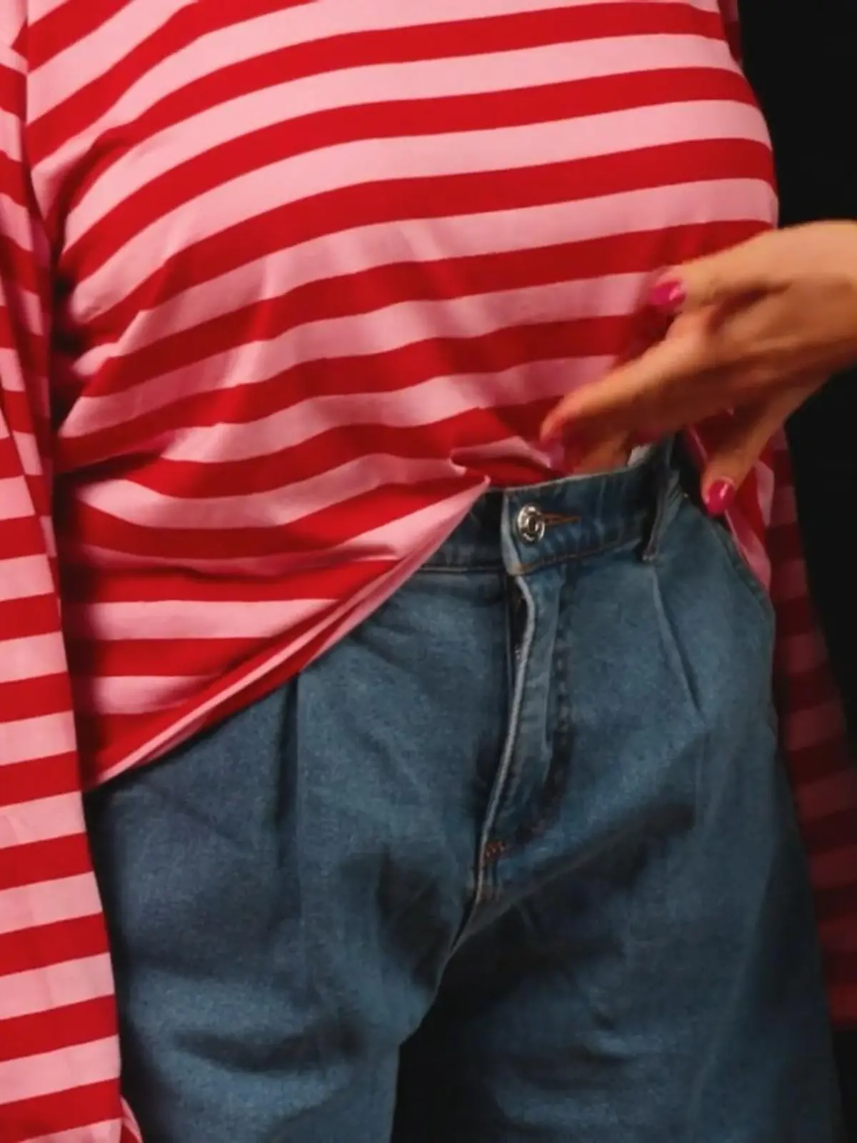 Frau steckt Oberteil in Jeans. 