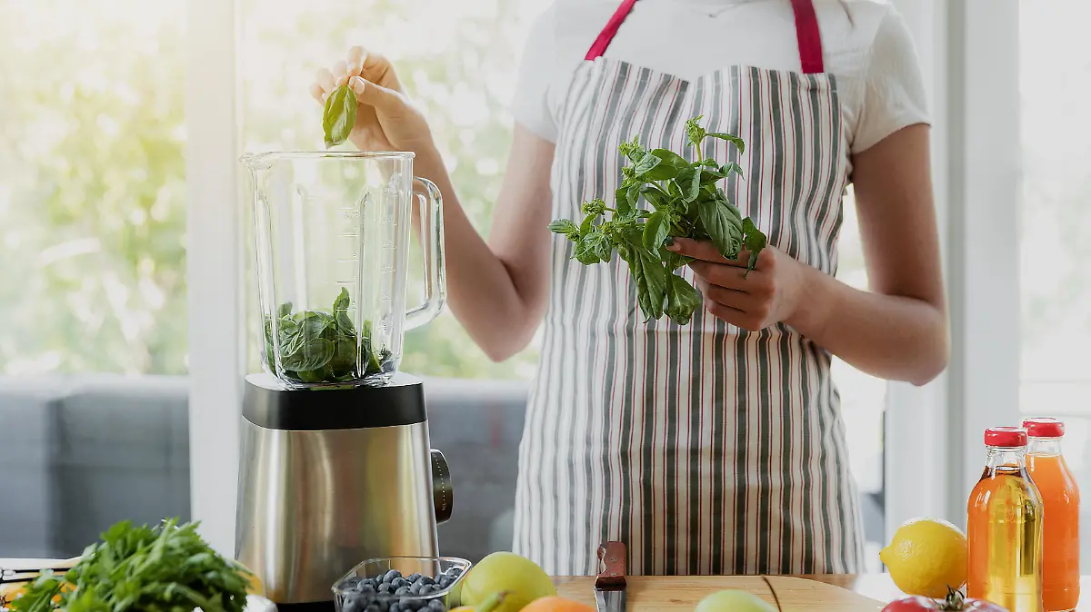 Junge Frau befüllt einen Standmixer in der Küche