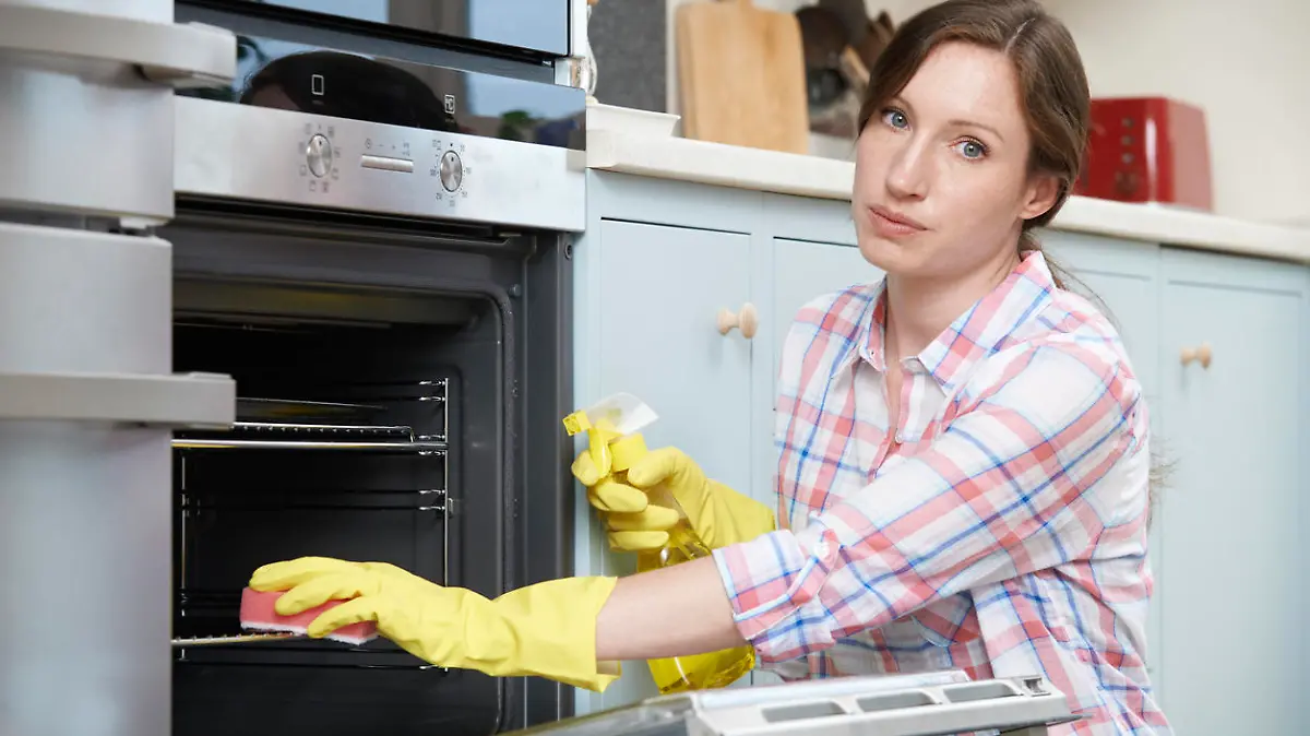 Portrait Of Fed Up Woman Cleaning Oven