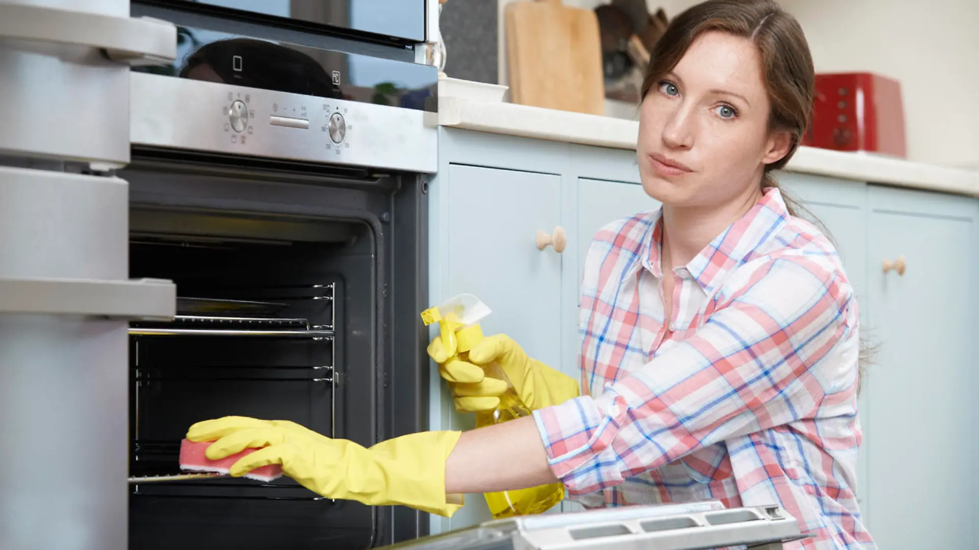 Portrait Of Fed Up Woman Cleaning Oven