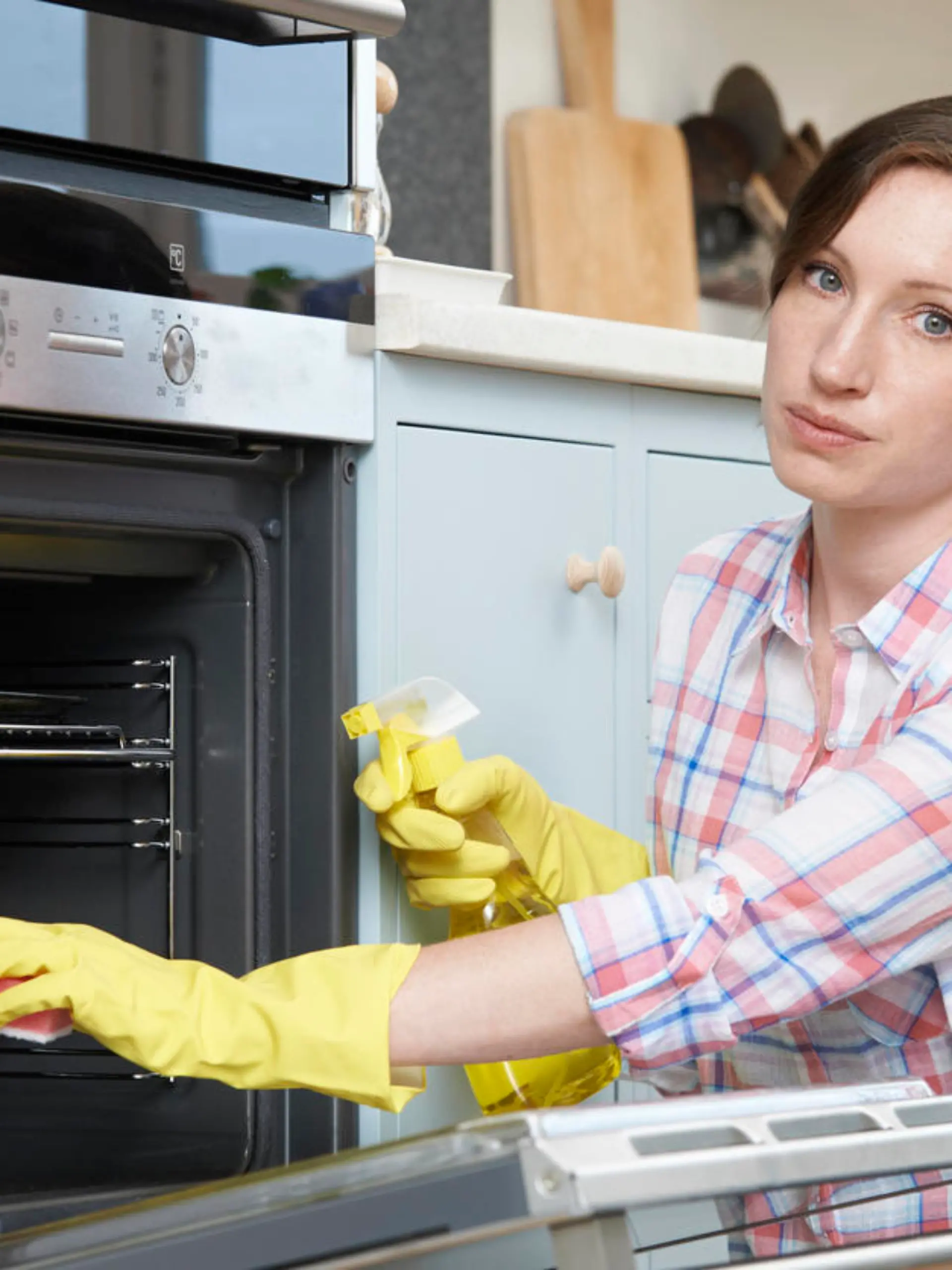 Portrait Of Fed Up Woman Cleaning Oven