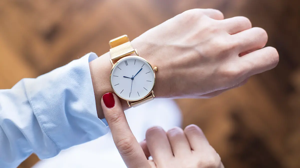 Handgelenk mit goldener Armbanduhr.