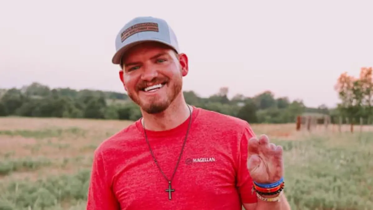 Dylan Riley steht auf einem Feld und zeigt seine amputierte linke Hand.