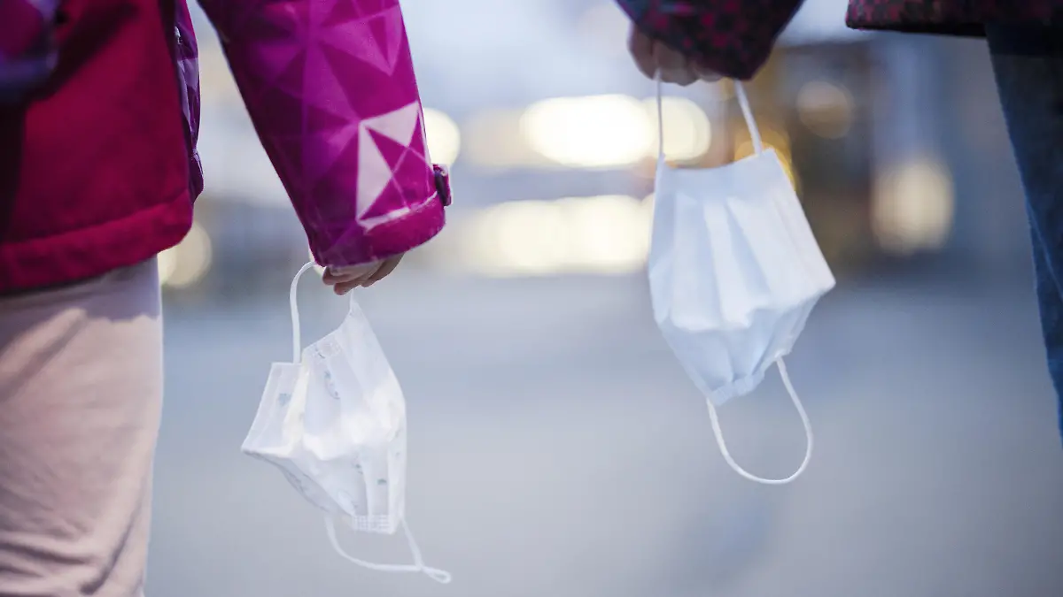 Primarschuelerinnen halten Kinder Masken auf einem Pausenplatz einer Schule, aufgenommen am Montag, 3. Januar 2022 in Zuerich. Die Maskentragpflicht im Kanton Zuerich wird mit dem Schulstart nach den Weihnachtsferien ab Montag, 3. Januar 2022 auf Schueler ab der 1. Primarschulklassen ausgeweitet. (KEYSTONE/Michael Buholzer)