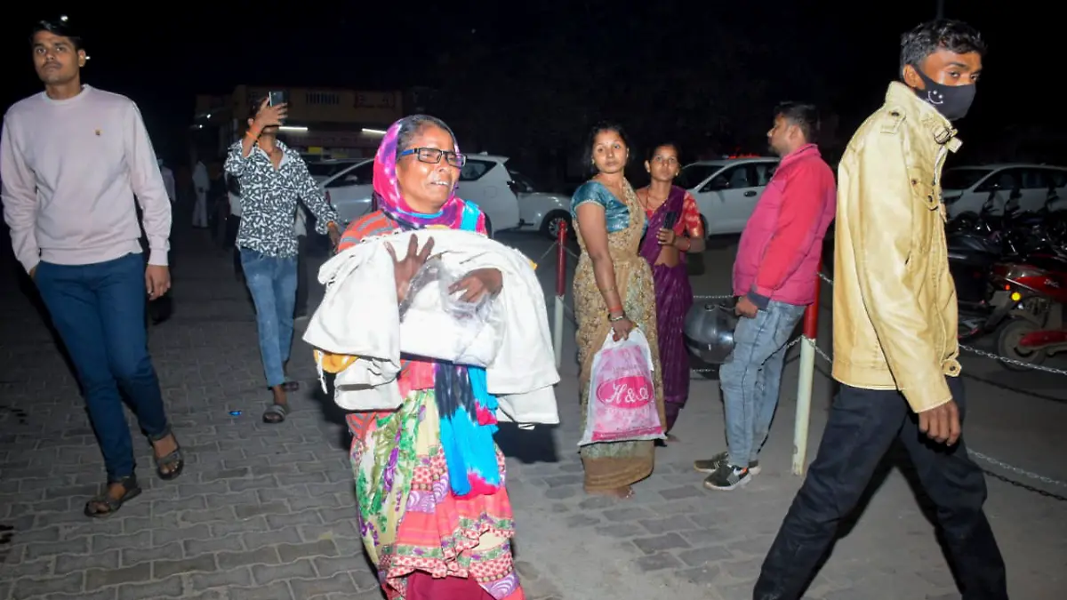 Eine Frau bringt ein Kind in die Notaufnahme, nachdem in der Neugeborenen-Intensivstation des Jhansi Medical College Krankenhauses ein Feuer ausgebrochen ist.