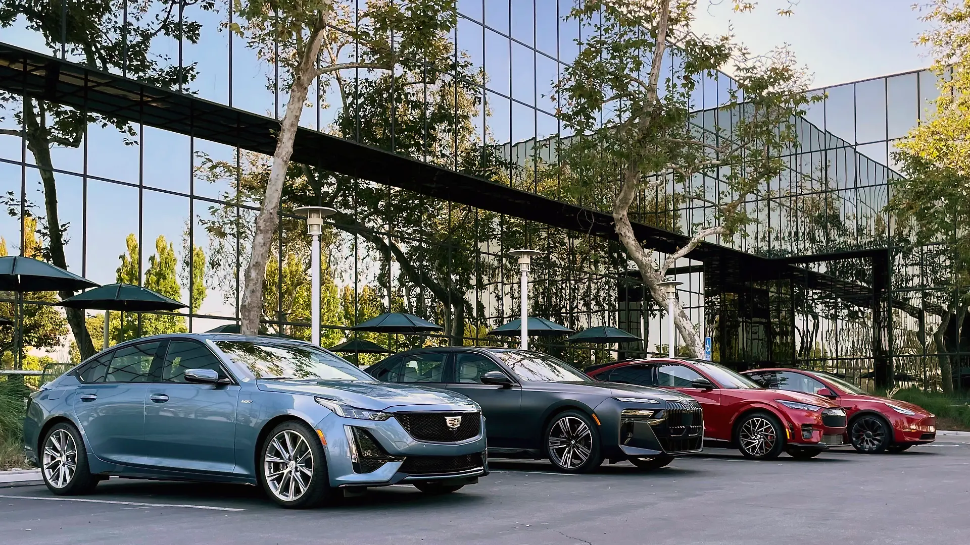 BMW, Cadillac und Tesla auf einem Parkplatz.