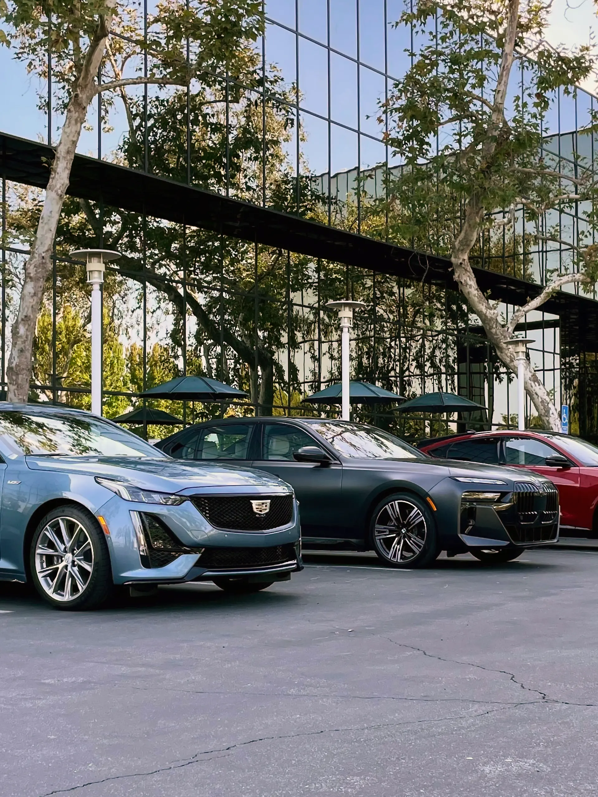 BMW, Cadillac und Tesla auf einem Parkplatz.