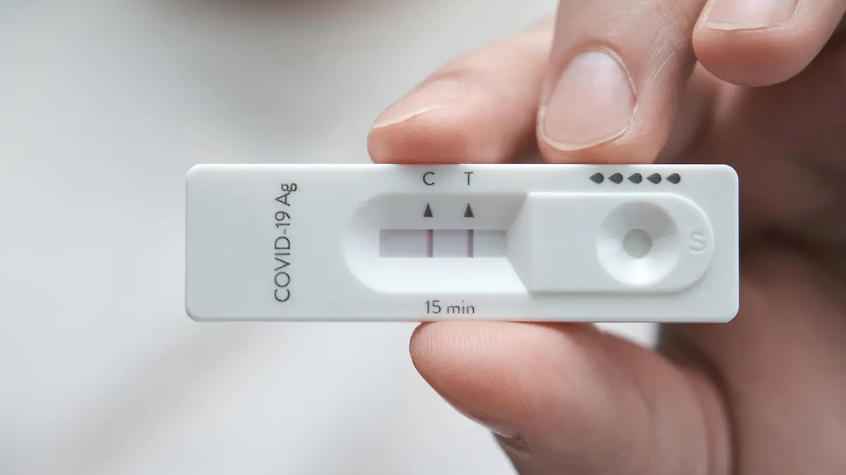Close-up of a hand holding a positive antigen test for COVID-19. SARS-CoV-2 antigen rapid test kit.