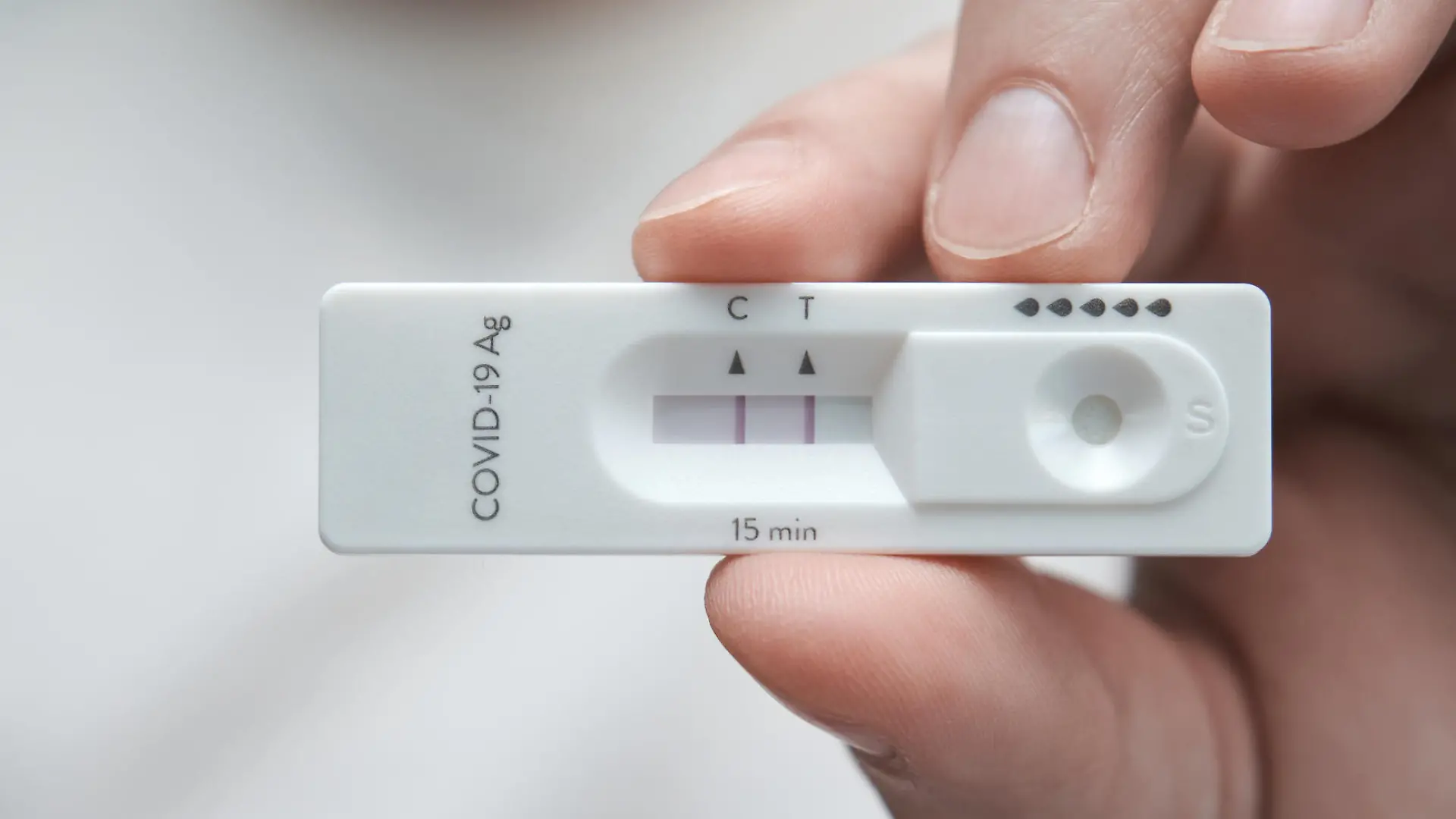 Close-up of a hand holding a positive antigen test for COVID-19. SARS-CoV-2 antigen rapid test kit.