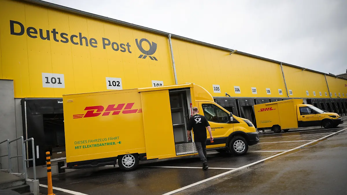 26.06.2023, Hamburg: Ein Mitarbeiter geht bei einem Fototermin zu einem elektrischen Zustellfahrzeug auf der neuen DHL-Zustellbasis. Die Deutsche Post DHL hat in Hamburg ihre bundesweit erste klimaneutrale Paket-Zustellbasis in Betrieb genommen. Die Basis im Stadtteil Schnelsen ist unter anderem mit einer Photovoltaik-Anlage, sechs Wärmepumpen für die Fußbodenheizung und 90 Ladepunkten für Elektro-Fahrzeuge ausgestattet. Foto: Christian Charisius/dpa +++ dpa-Bildfunk +++