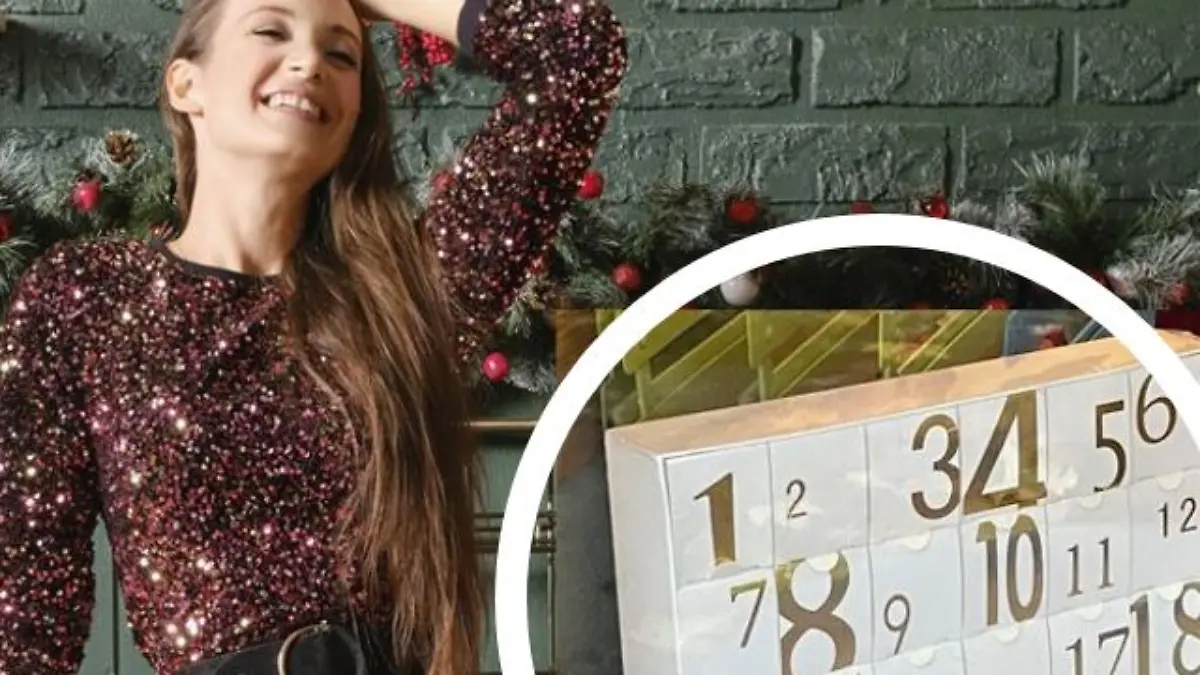 Frau im glitzernden Rock steht an Küchenzeile und lacht während sie mit einer Hand die Haare zurückhält, daneben ein weiß-goldener Adventskalender.