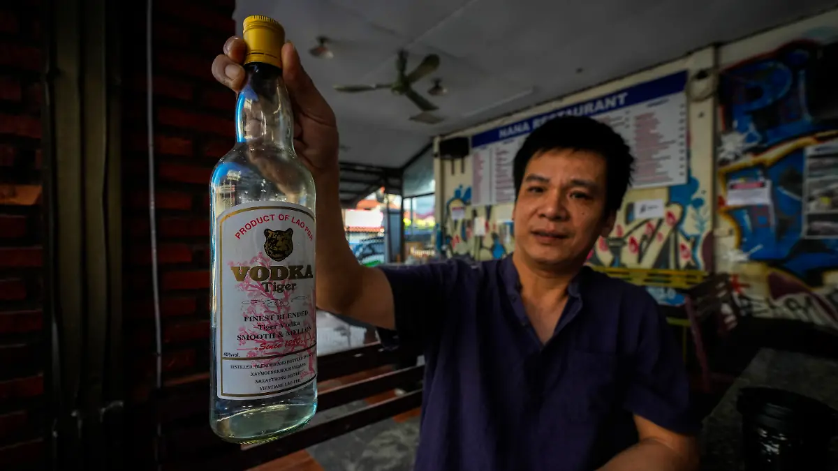 Duong Duc Toan, the manager of Nana Backpack hostel displays a bottle of vodka, in the bar of the hostel in Vang Vieng, Laos, Tuesday, Nov. 19, 2024.