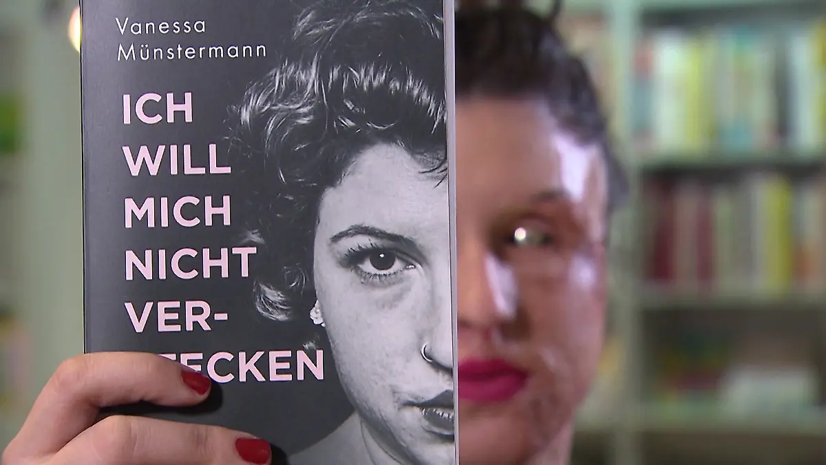 Eine Frau hält ein Buch vor ihr Gesicht.