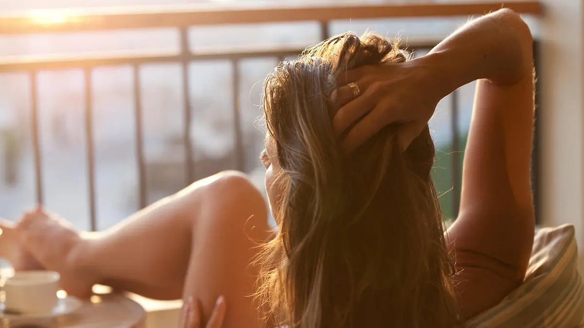 Woman relaxing at balcony enjoying sunrise. Good morning