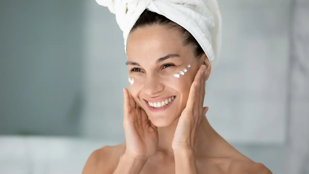 Eine Frau cremt sich nach dem Duschen das Gesicht ein. Sie nutzt eine Anti-Aging-Pflege.