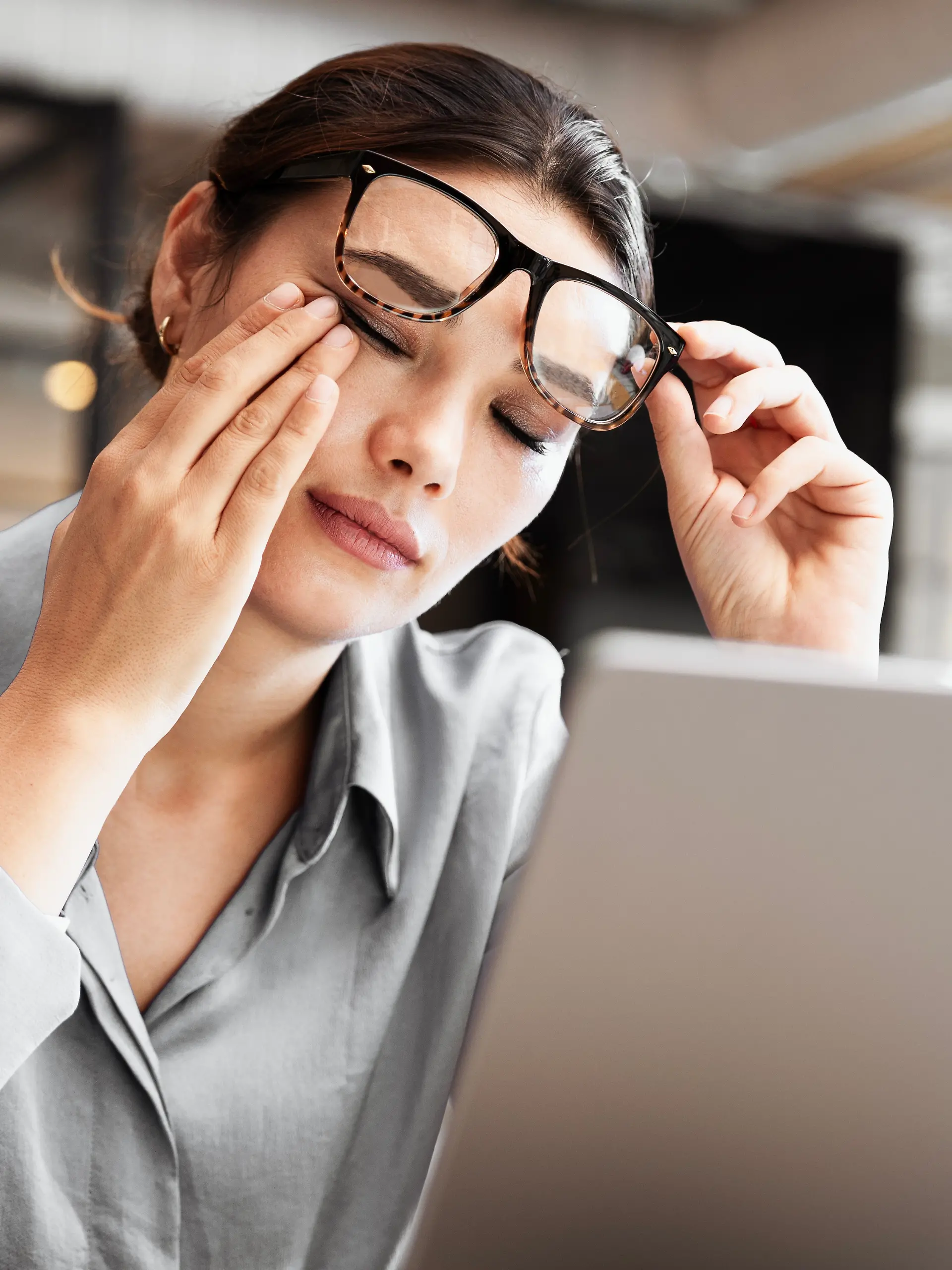 Frau reibt sich die Augen bei der Arbeit am Bildschirm
