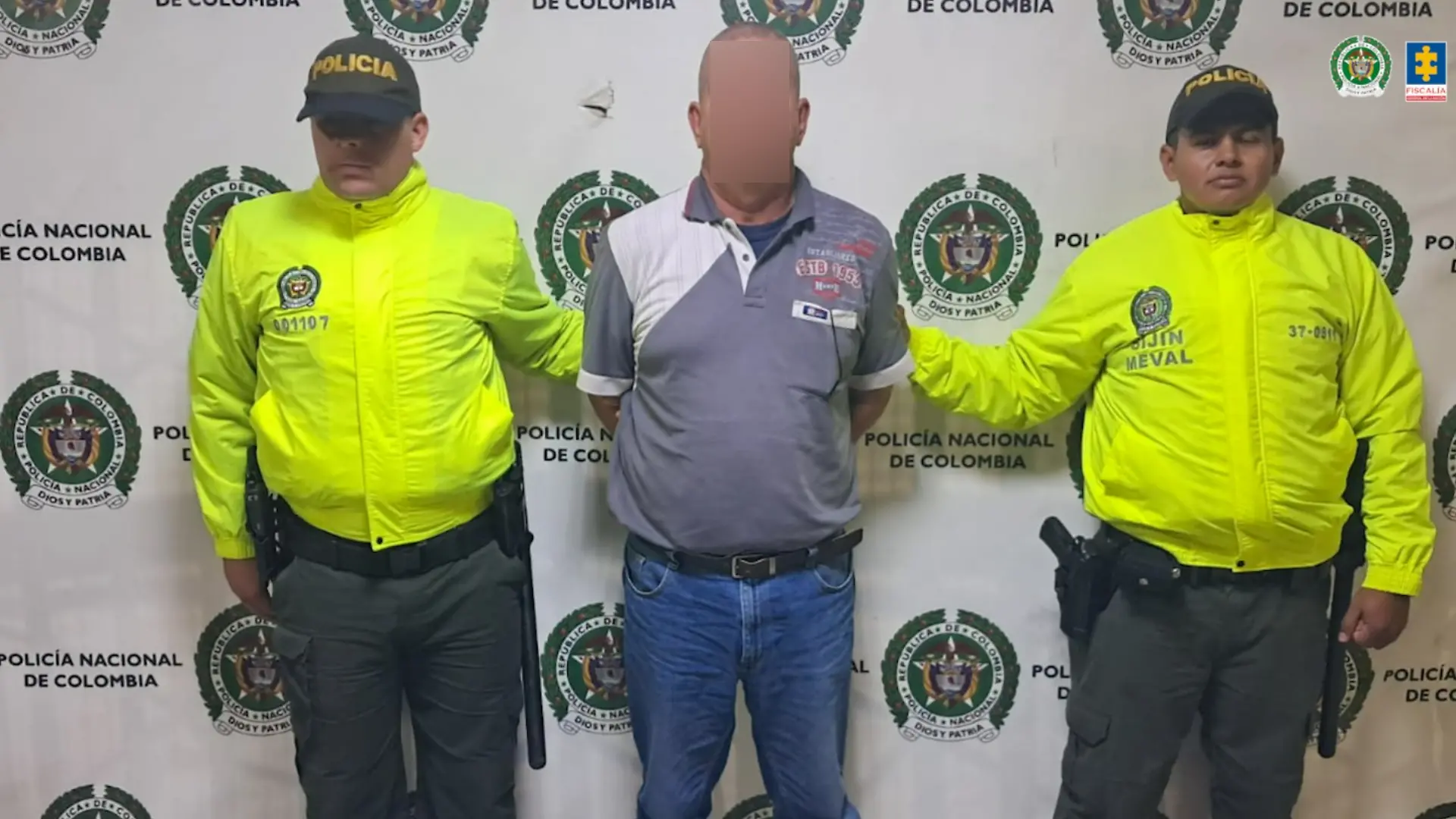 Ein Mann steht in Handschellen zwischen zwei Polizisten. 