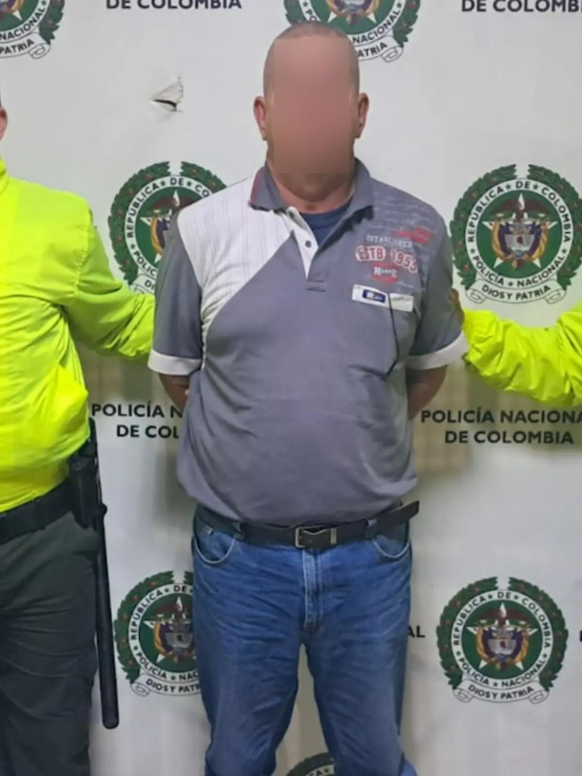 Ein Mann steht in Handschellen zwischen zwei Polizisten. 