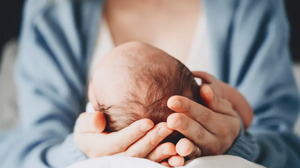 Eine Frau hält ihr neugeborenes Baby im Arm.