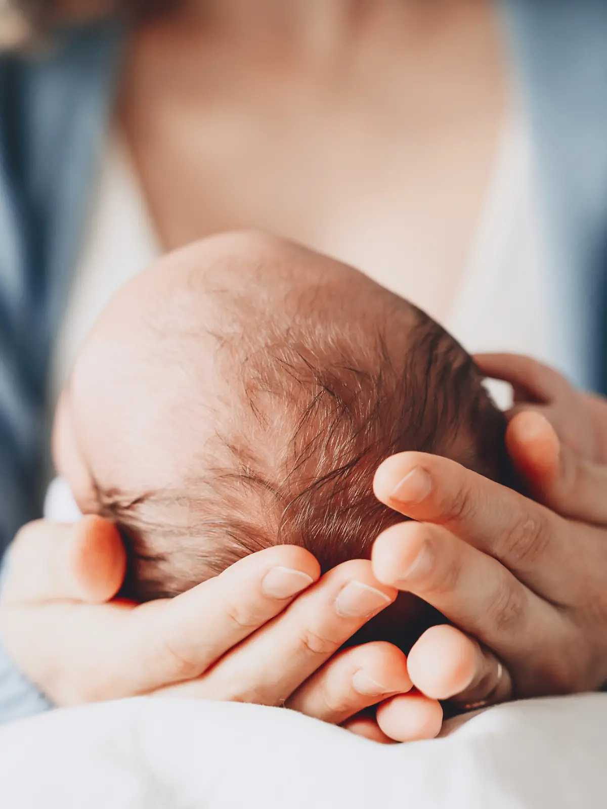 Eine Frau hält ihr neugeborenes Baby im Arm.