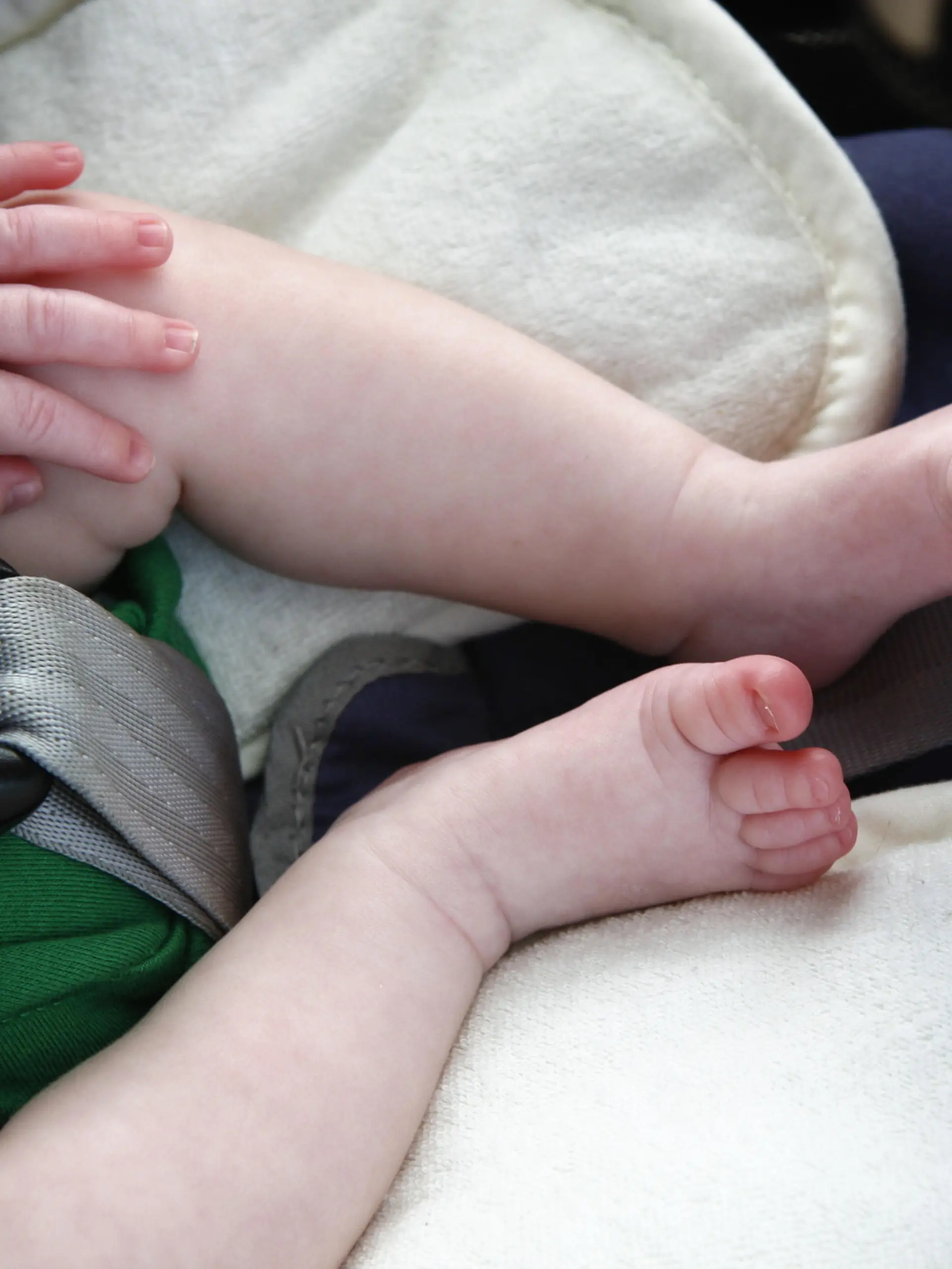Legs and hand of little child in car seat.