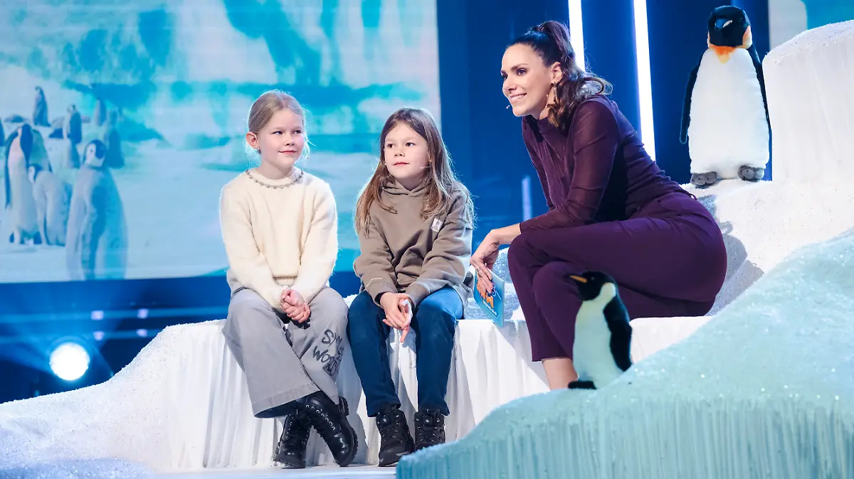 Mira (10) und Adam (8) fragen, ob Pinguine kalte Füße haben. Rechts daneben Moderatorin Esther Sedlaczek.
