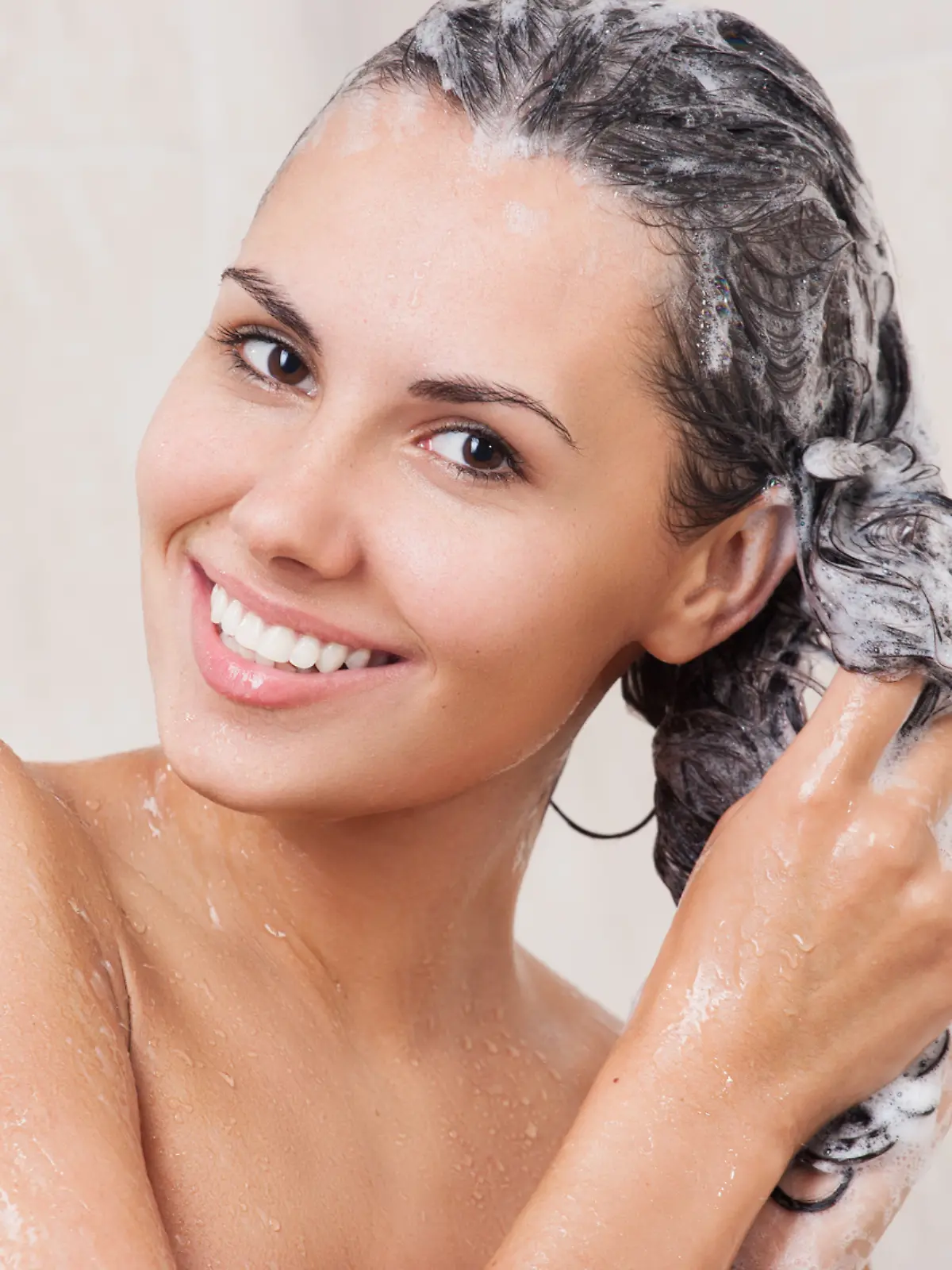 Young woman washing her head in the shower by shampoo