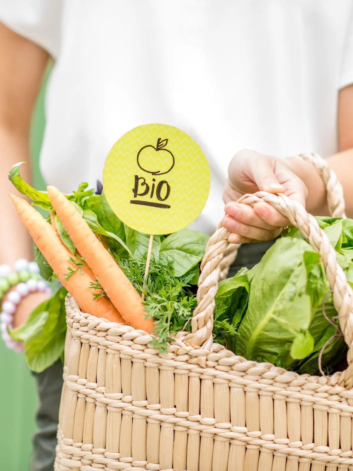 Holding bag full of fresh organic vegetables with green sticker from the local market on the green background