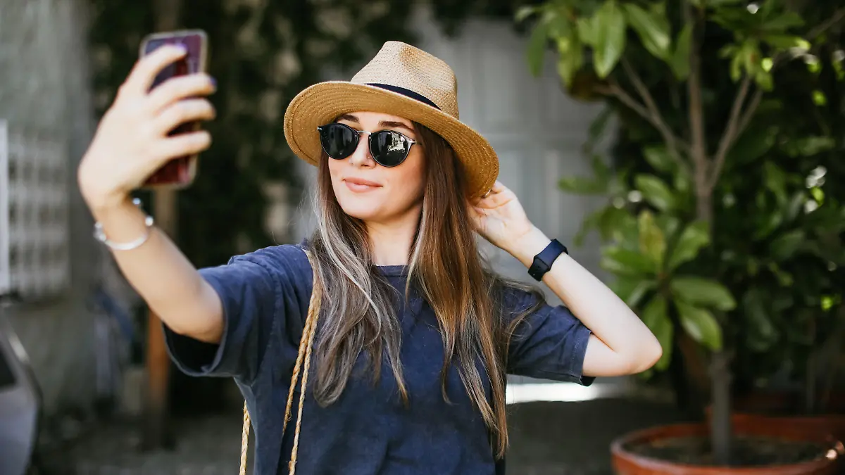 Portrait outdoors of a beautiful young woman taking a picture with mobile phone.