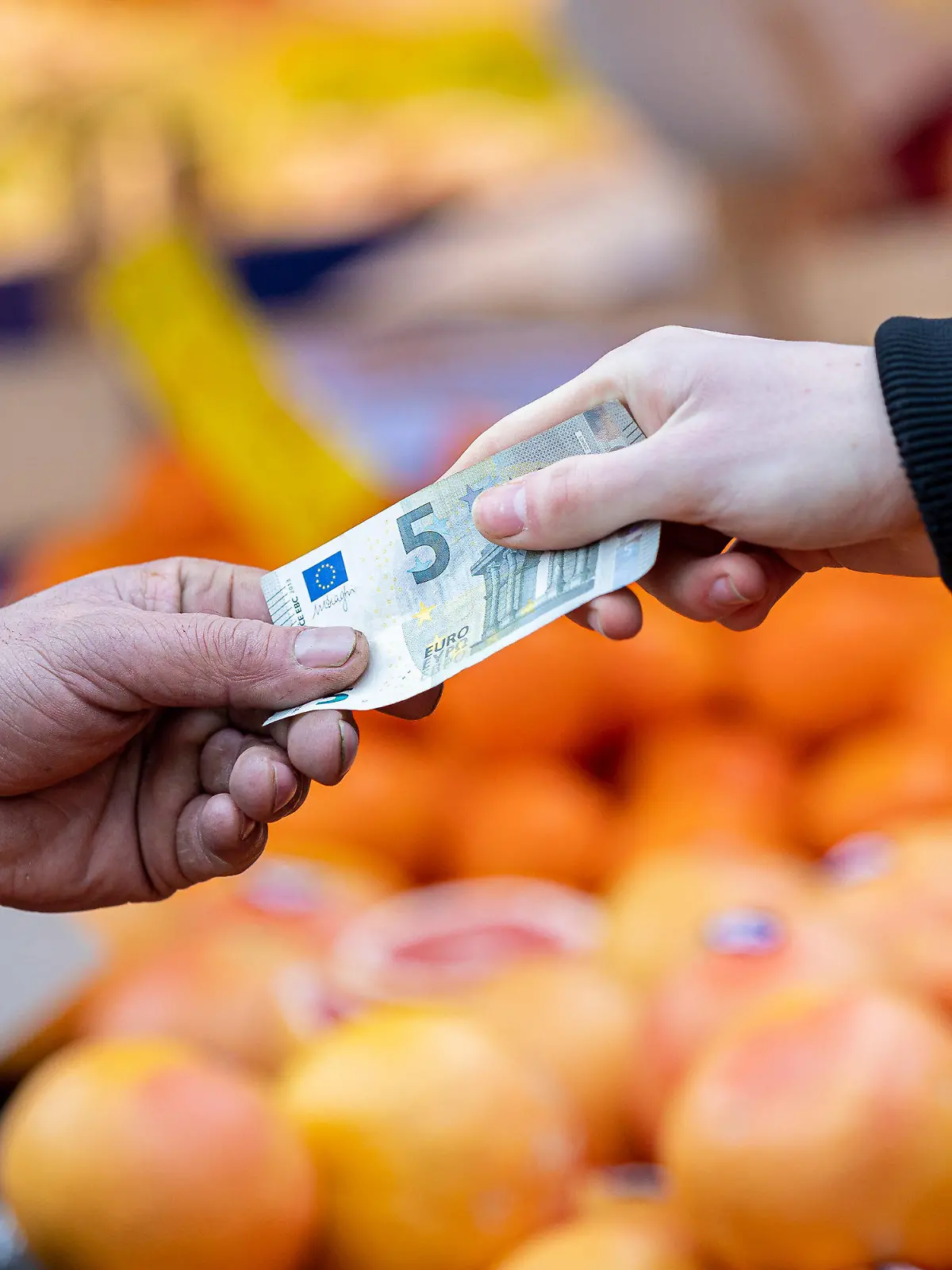 ARCHIV - 29.01.2022, Niedersachsen, Hannover: ILLUSTRATION - Ein Kunde bezahlt seinen Einkauf an einem Stand auf einem Wochenmarkt mit einem Fünf-Euro-Schein (gestellte Szene). Die Lebensmittelpreise steigen deutlich. Nun gibt es in der EU neue rechtliche Möglichkeiten zur Senkung der Mehrwertsteuer.(zu dpa: «Verbände fordern Mehrwertsteuersenkung auf Null bei Lebensmitteln») Foto: Moritz Frankenberg/dpa +++ dpa-Bildfunk +++