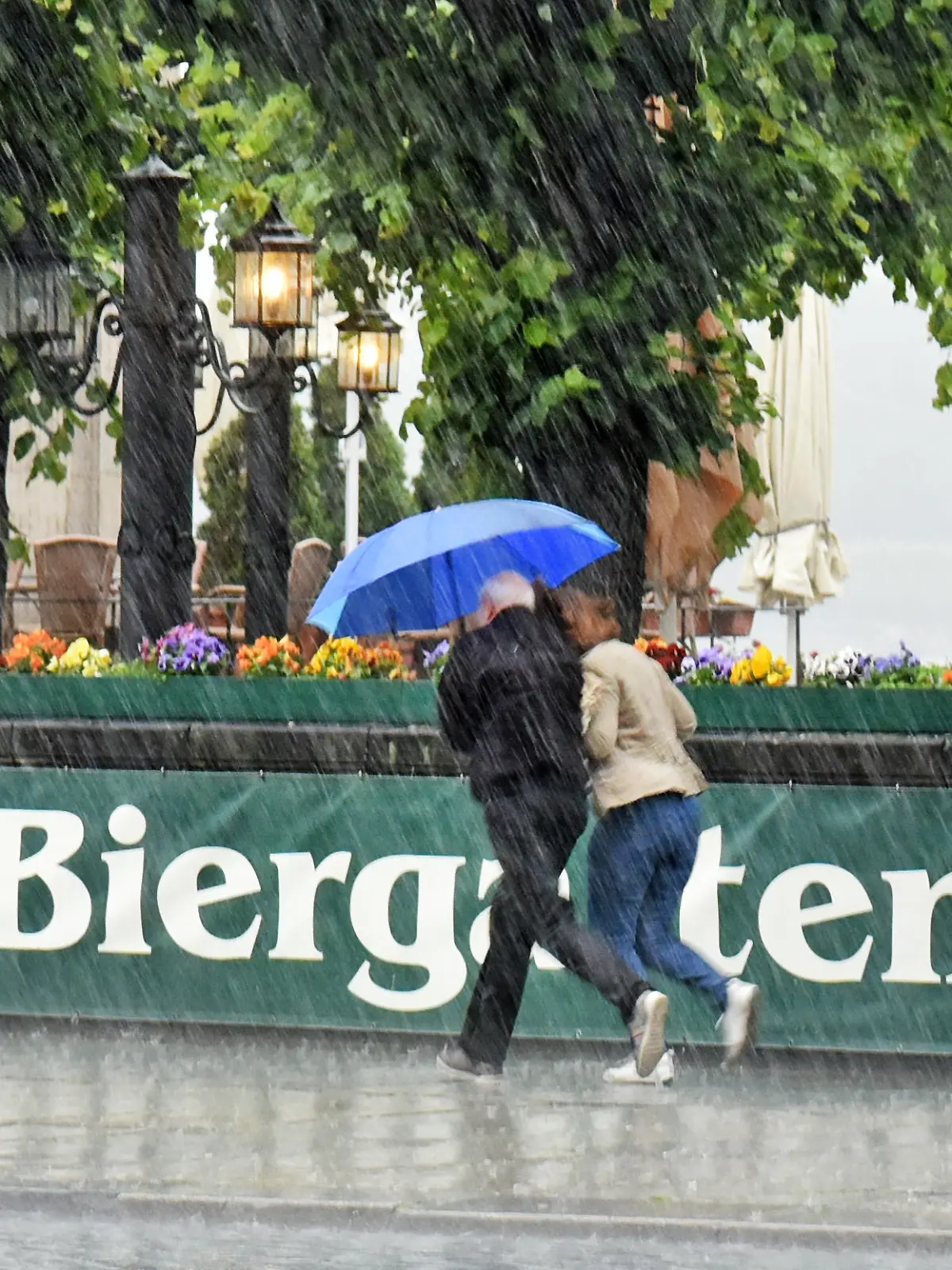Ein Paar rennt am 01.06.2015 in Dresden (Sachsen) im Stadtzentrum bei einem Gewitterregen an einem Biergarten vorbei. Foto: Matthias Hiekel +++(c) ZB-FUNKREGIO OST - Honorarfrei nur für Bezieher des ZB-Regiodienstes+++ | Verwendung weltweit