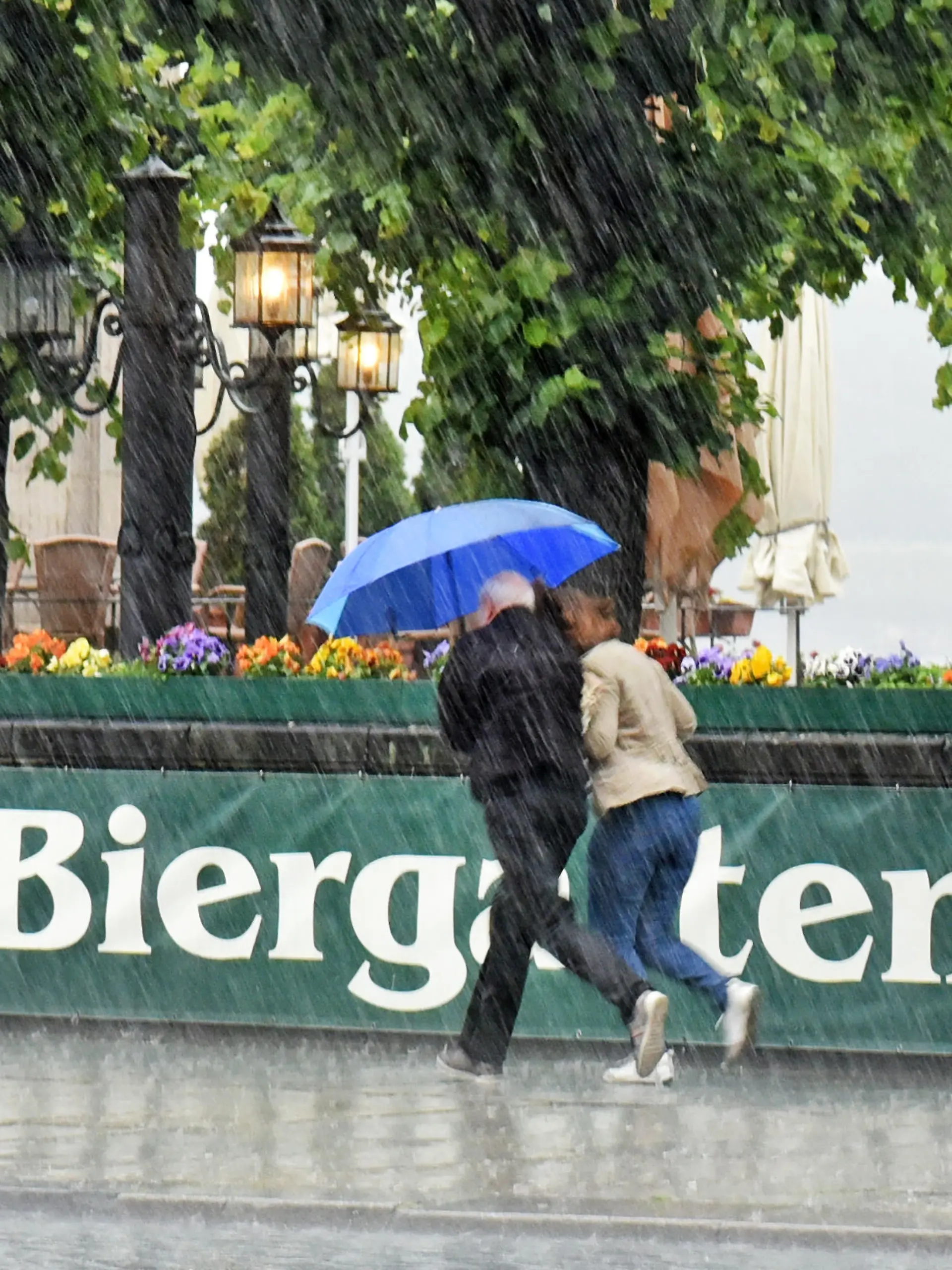 Ein Paar rennt am 01.06.2015 in Dresden (Sachsen) im Stadtzentrum bei einem Gewitterregen an einem Biergarten vorbei. Foto: Matthias Hiekel +++(c) ZB-FUNKREGIO OST - Honorarfrei nur für Bezieher des ZB-Regiodienstes+++ | Verwendung weltweit