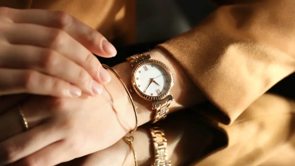 Goldene Armbanduhr am Handgelenk einer Frau.