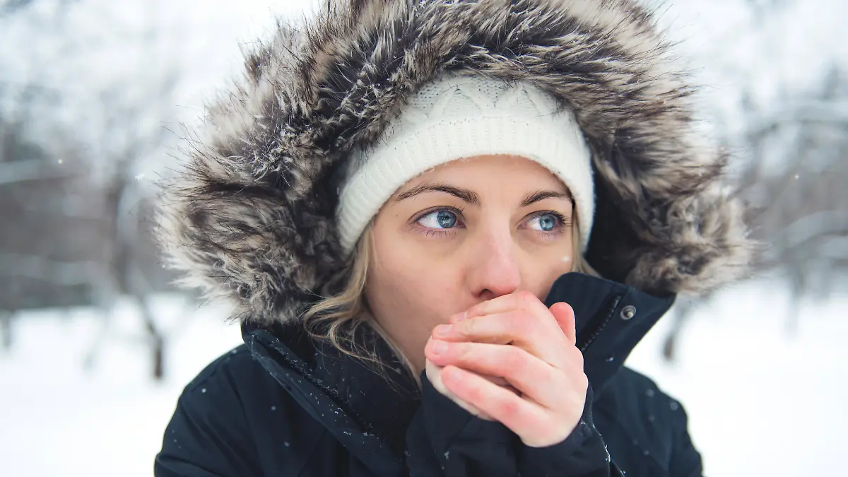 Mädchen pustet sich die kalten Hände warm.