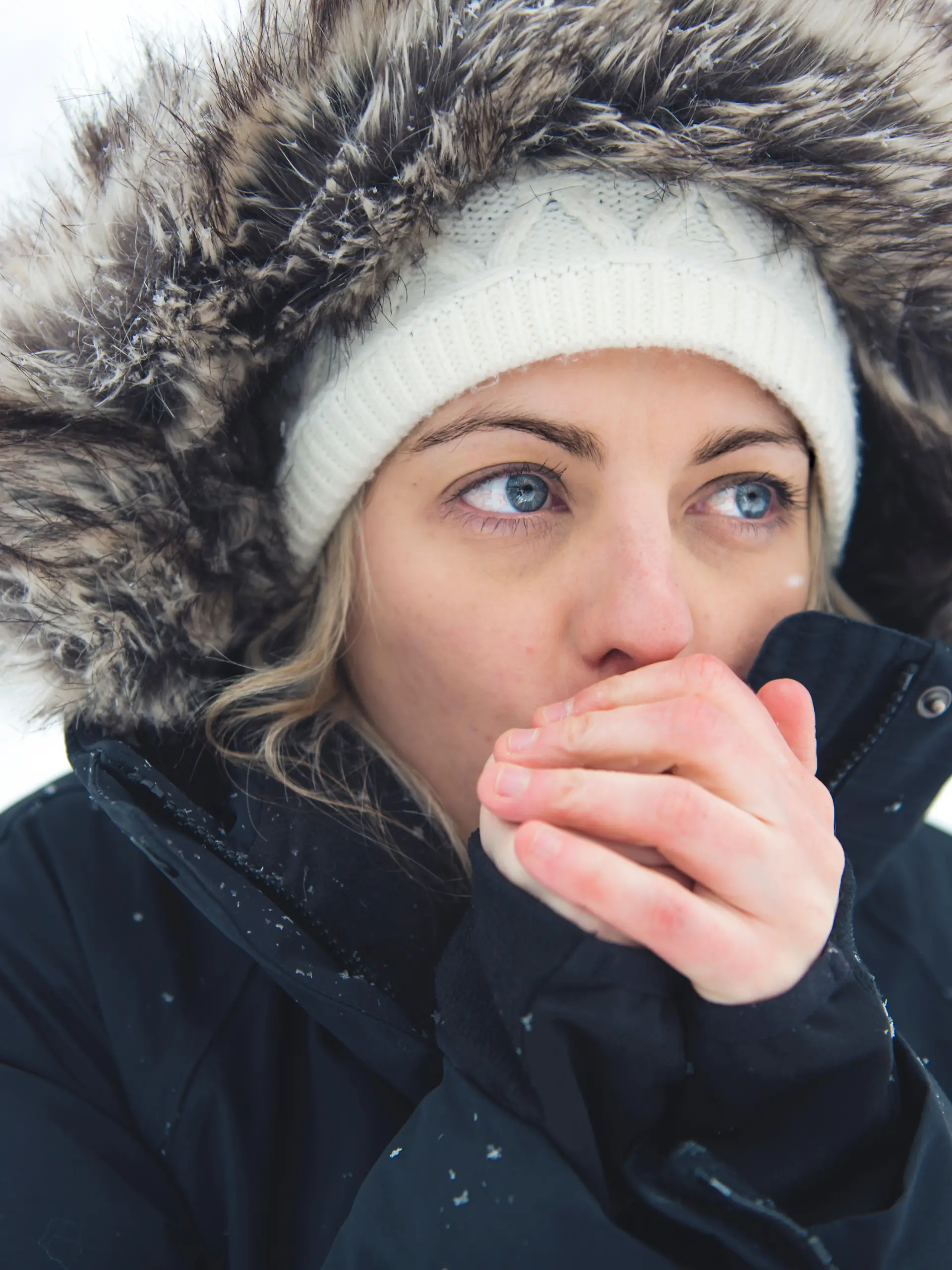 Mädchen pustet sich die kalten Hände warm.