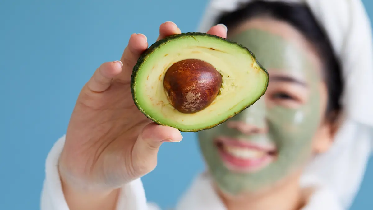 Frau mit Maske hälte Avocado ins Bild