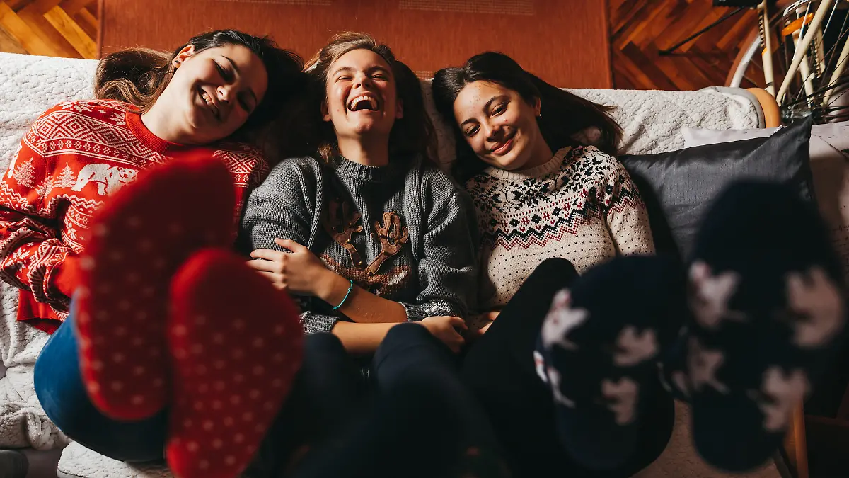 Eine Gruppe von Freundinnen chillt gemeinsam an Weihnachten auf dem Sofa und hat eine gute Zeit.