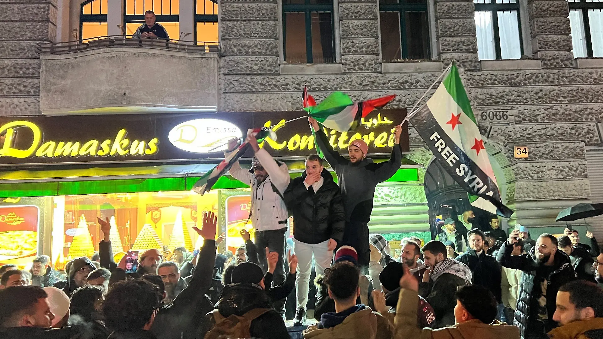 Syrer versammeln sich im Bezirk Neukölln mit Flaggen vor der Bäckerei Damaskus und feiern den Vormarsch der Rebellen auf Damaskus. Aufständische übernehmen in Syrien mit hoher Geschwindigkeit die Kontrolle über Städte und ganze Landstriche.