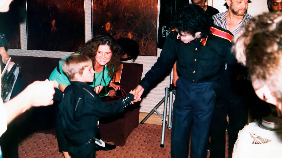 This image released by HBO shows a young Wade Robson shaking hands with pop icon Michael Jackson in 1987, in a scene from the documentary "Leaving Neverland." A trio of high-profile child sexual abuse documentaries have generated intense scrutiny of parents. But what critics with no experience of their own may not realize, experts say, is parents of young victims can be groomed by perpetrators along with their children. (Dan Reed/HBO via AP)