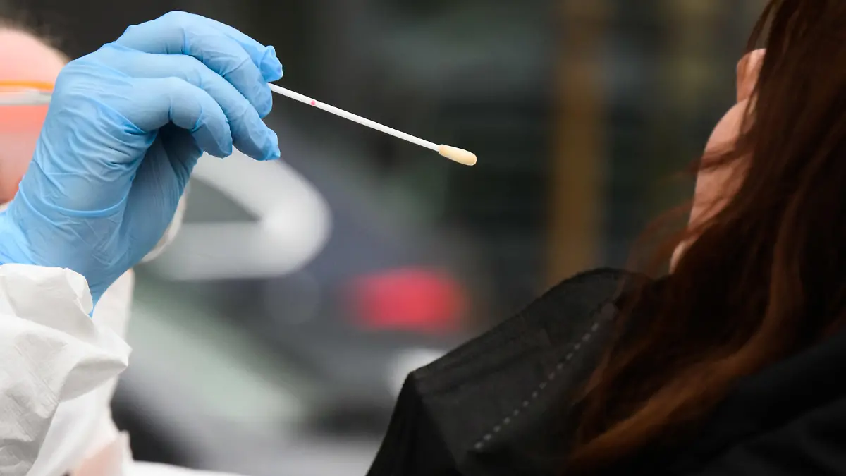 26.01.2022, Niedersachsen, Laatzen: Eine Hausärztin nimmt einen Abstrich von einer Patientin für einen PCR-Test auf das Corona-Virus vor einer Arztpraxis in der Region Hannover. Erstmals in der Corona-Pandemie sind binnen eines Tages mehr als 150 000 Neuinfektionen an das Robert Koch-Institut übermittelt worden. Wegen der sprunghaft steigenden Infektionszahlen reichen die derzeitigen Kapazitäten für die besonders genauen PCR-Tests nicht mehr aus. Foto: Julian Stratenschulte/dpa +++ dpa-Bildfunk +++