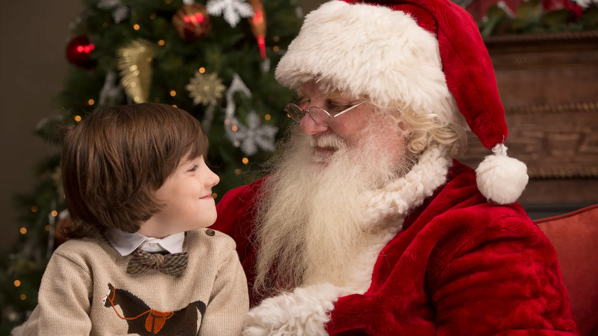 Ein Junge sitzt auf dem Schoß vom Nikolaus / dem Weihnachtsmann.