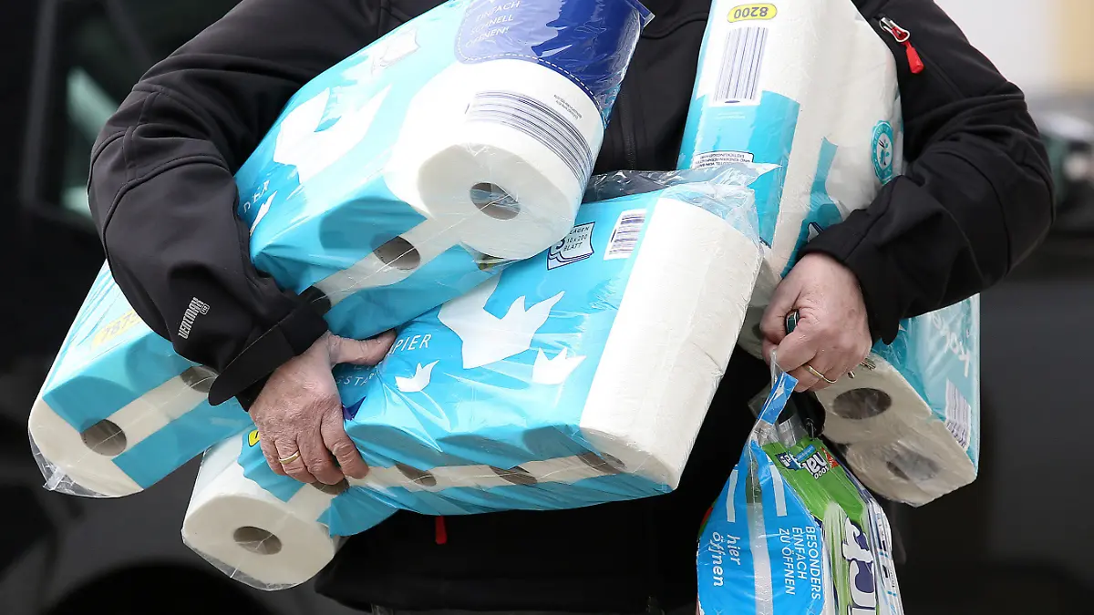 ARCHIV - 18.03.2020, Nordrhein-Westfalen, Siegen: Ein Mann trägt eingekauftes Toilettenpapier und Küchenrollen aus einem Supermarkt. (zu dpa «Spätfolgen der Hamsterkäufe: Papierbranche verkauft weniger Klopapier») Foto: Rene Traut/dpa +++ dpa-Bildfunk +++