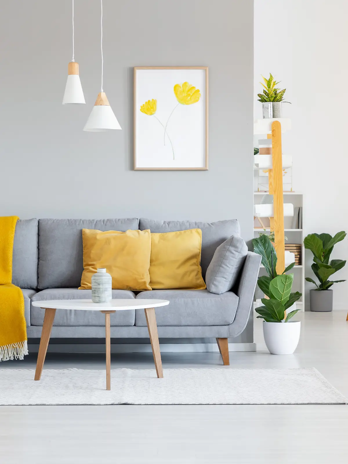 Orange blanket on grey sofa in modern apartment interior with poster and wooden table. Real photo