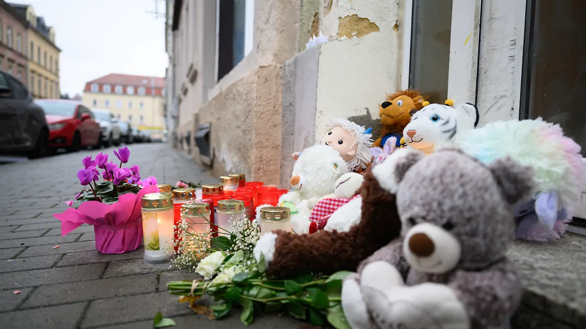 10.12.2024, Sachsen, Meißen: Blumen und Kuscheltiere sind vor einem Haus abgelegt. In einem Mehrfamilienhaus in der Straße sind drei Kleinkinder im Alter von einem, zwei und drei Jahren sowie ein 37-jähriger Mann tot gefunden worden. Die Ermittler gehen von einem Tötungsdelikt aus, wie sie am Montag mitteilten. Foto: Robert Michael/dpa +++ dpa-Bildfunk +++
