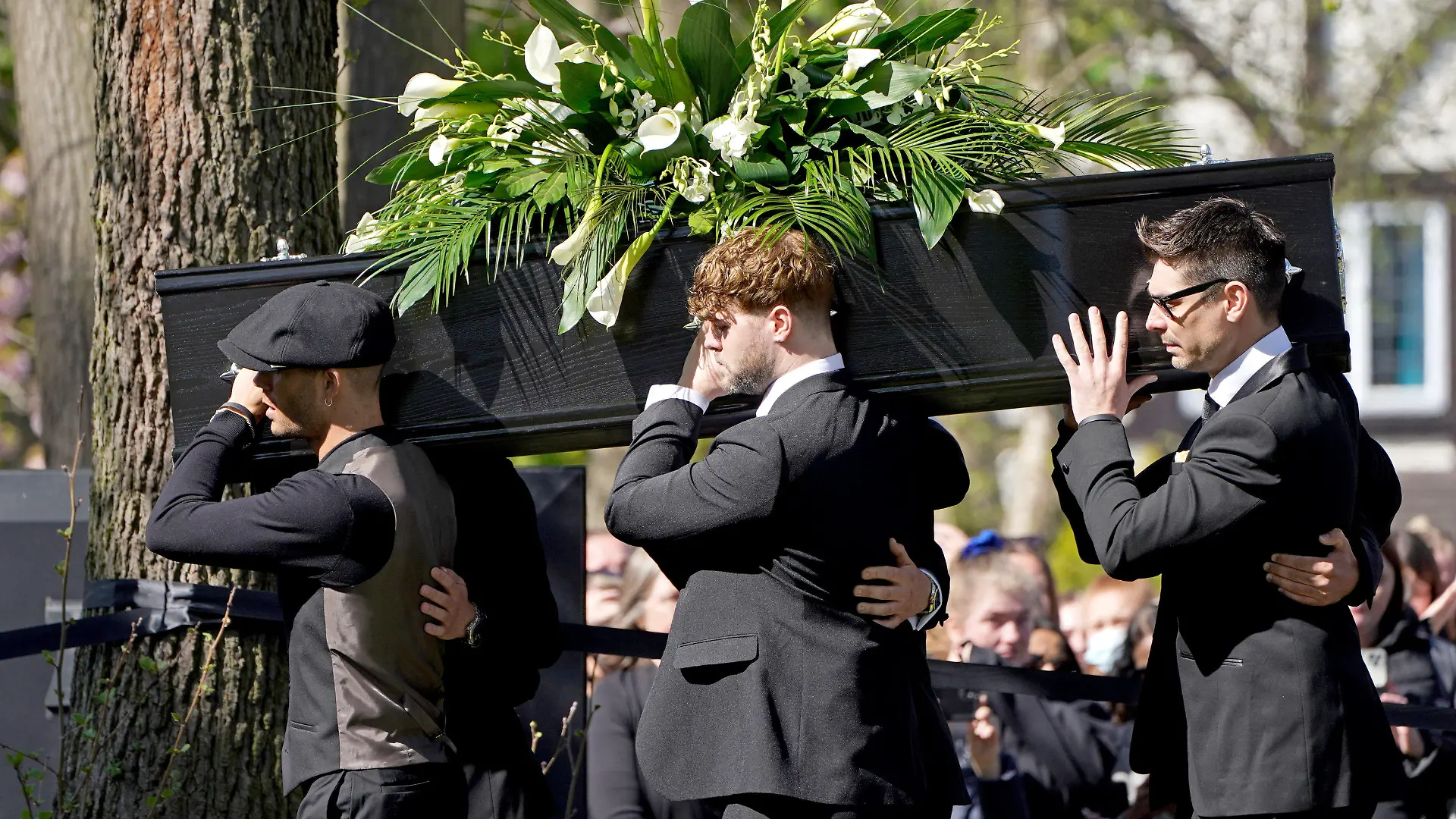 20.04.2022, Großbritannien, London: Max George (l) und Jay McGuiness (M), Mitglieder der Band «The Wanted», tragen den Sarg von Parker in die Kirche. Der britische Sänger Tom Parker von der Boygroup «The Wanted» war 17 Monate nach einer Diagnose eines inoperablen Hirntumors im Alter von 33 Jahren gestorben. Foto: Kirsty O'connor/PA Wire/dpa +++ dpa-Bildfunk +++