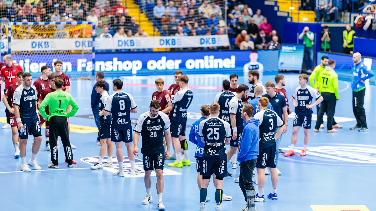 Die Spieler des TBV Lemgo und VfL Potsdam stehen auf dem Platz und warten auf Informationen.