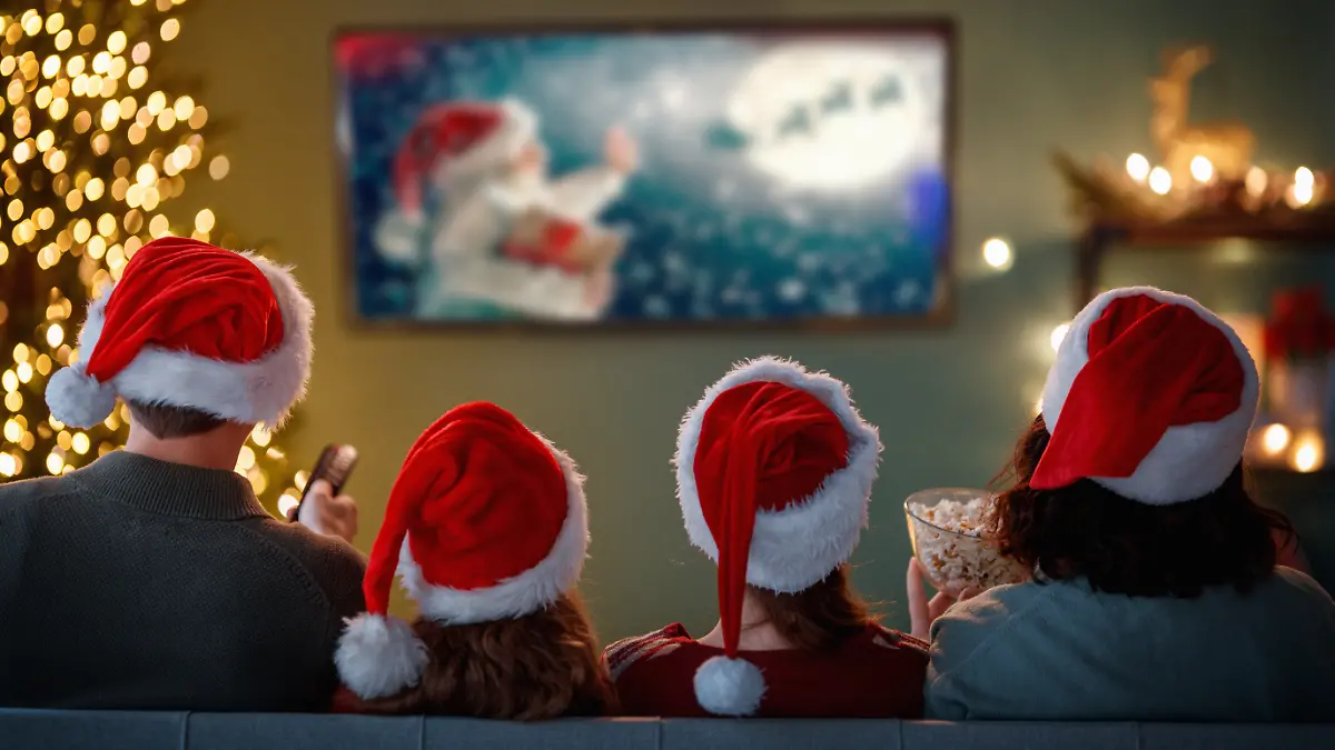 Familie sitzt mit Nikolausmützen vor dem Fernsehr 