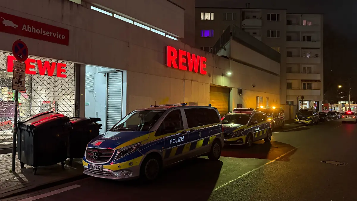 Die Polizeiautos stehen vor dem Rewe-Markt am Salierring in Köln.