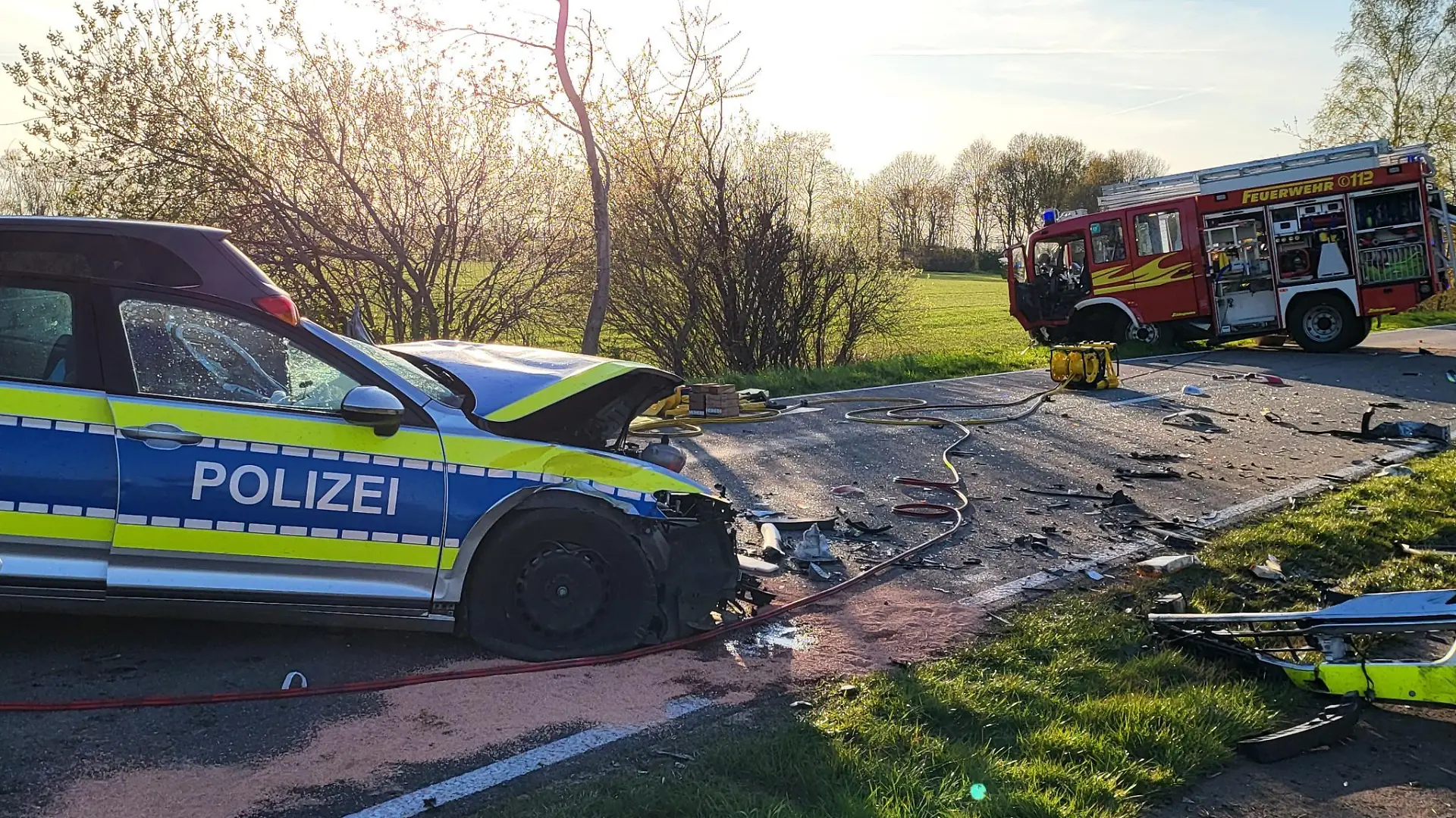 19.04.2022, Niedersachsen, Hoogstede: Ein beschädigtes Polizeiauto und ein Einsatzfahrzeug der Feuerwehr stehen am Unfallort. Bei einem Frontalzusammenstoß zwischen Polizei und Feuerwehr bei Hoogstede im Landkreis Grafschaft Bentheim auf dem Weg zu einem Brand sind zwei Polizisten verletzt worden. Foto: ---/Nord-West-Media TV /dpa +++ dpa-Bildfunk +++